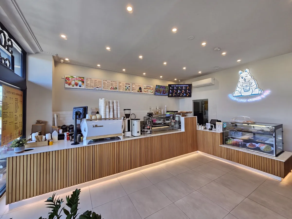 Inside Scent-tastic: the long timber counter, the white coffee machine and the blue neon squirrel on the wall