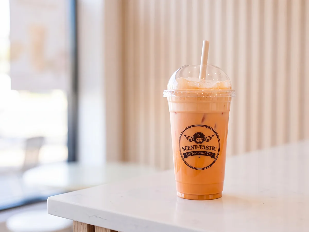 An iced milk tea in a Scent-tastic cup on the white counter by the window